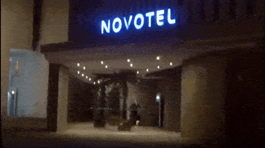 a person in sports dress doing rope skipping at night in front of a hotel entrance