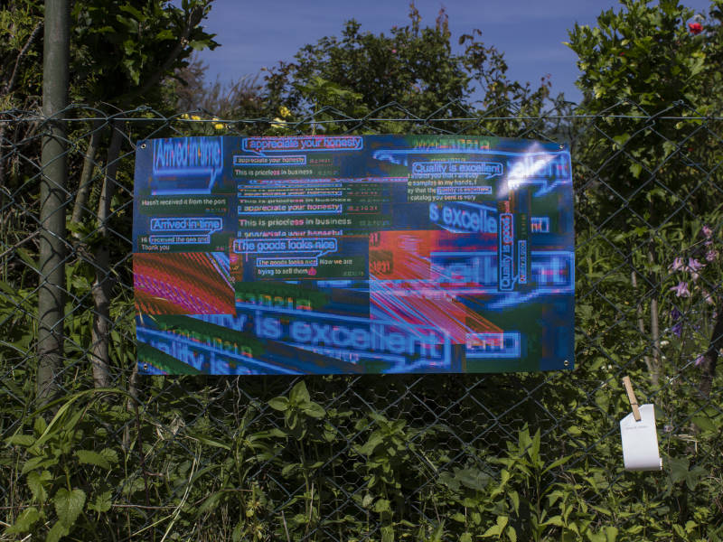digital collage with glitched screenshots of a trading and resellers customer chat protocol, printed on pvc canvas, attached to a garden fence. summer garden plants surround the artwork