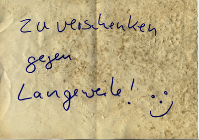 piece of paper with handwritten words “Zu Verschenken Gegen Langeweile” (Give Away against boredom), and a smiley face