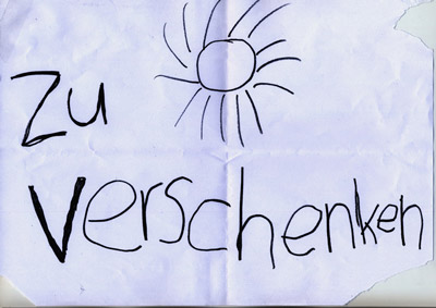 piece of paper with handwritten words “Zu Verschenken” (Give Away), and a drawing of a sun